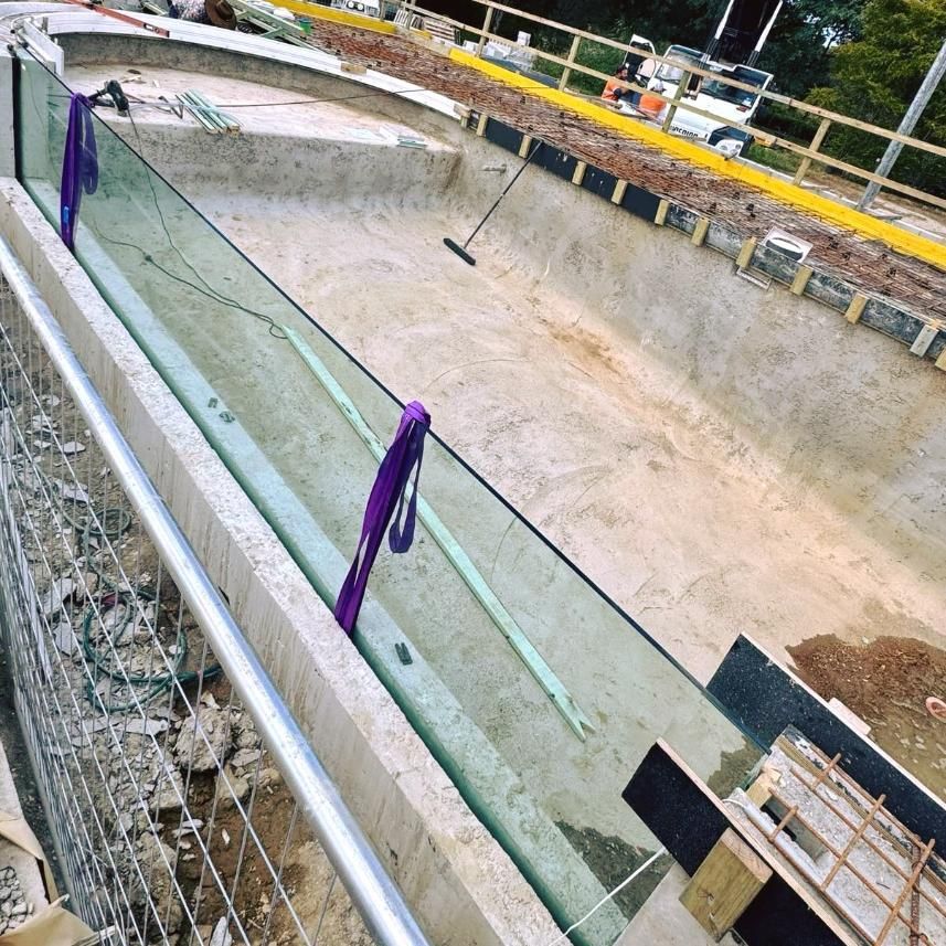 A Swimming Pool Is Being Built With A Glass Fence Around It — Glass Pool Windows Australia In Rockhampton, QLD