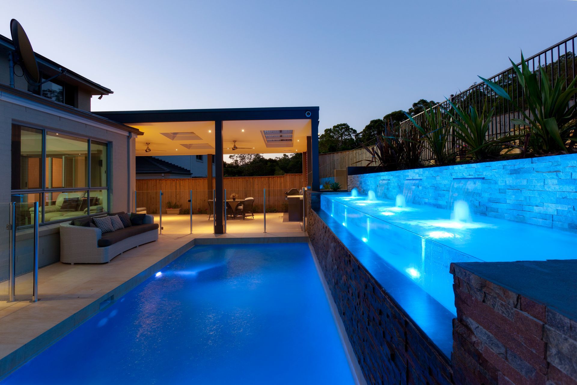 A Large Swimming Pool Is Lit Up With Blue Lights — Glass Pool Windows Australia In Old Bar, NSW