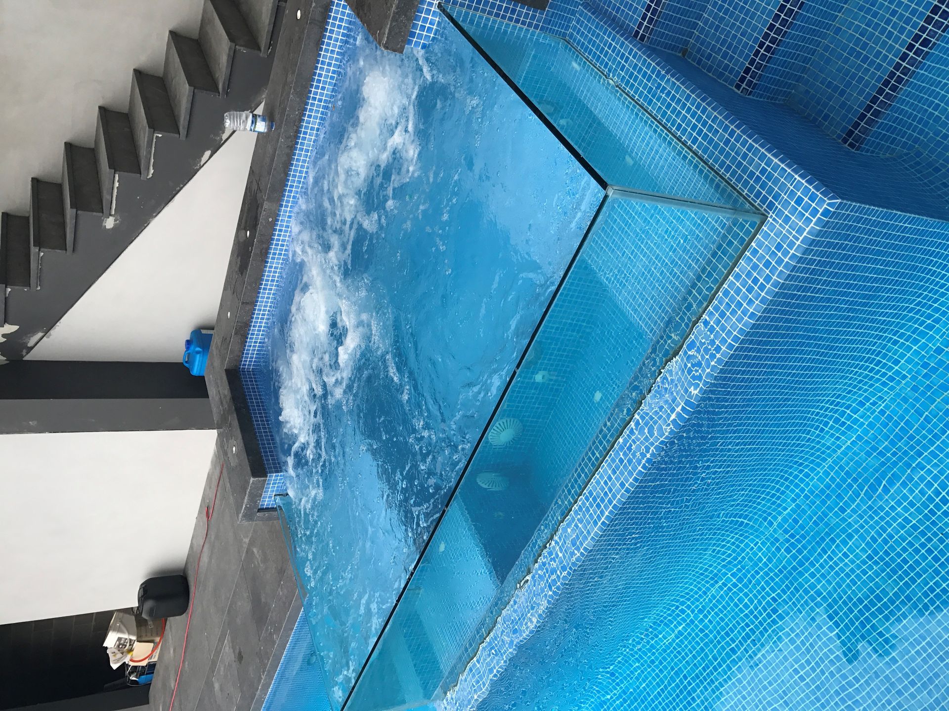 A Swimming Pool With A Clear Glass Wall And Stairs In The Background — Glass Pool Windows Australia In Old Bar, NSW