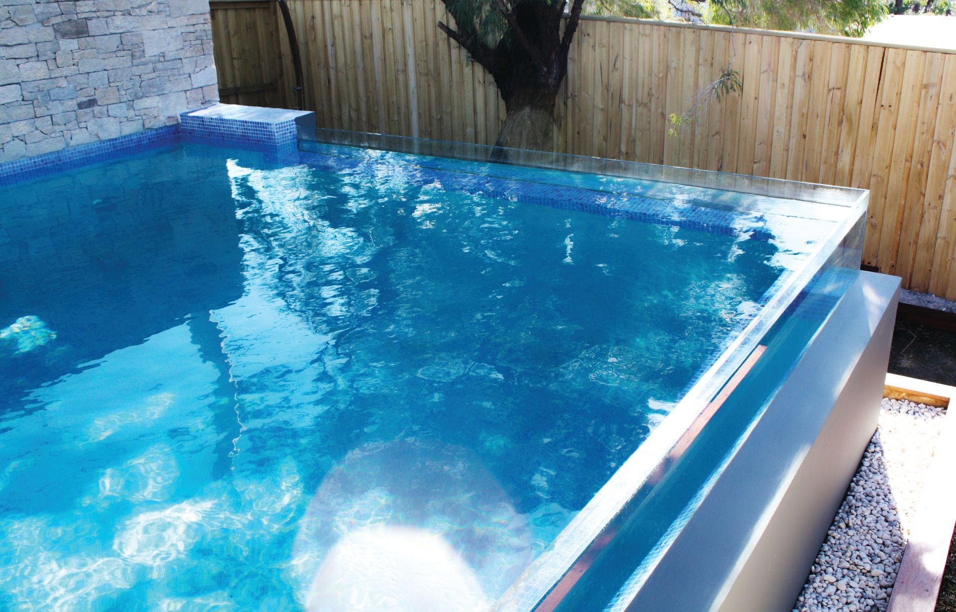 A Large Swimming Pool Is Surrounded By A Wooden Fence — Glass Pool Windows Australia In Old Bar, NSW