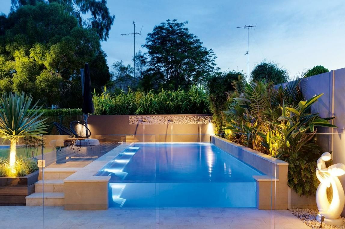 A Large Swimming Pool Is Lit Up At Night In A Backyard — Glass Pool Windows Australia In Old Bar, NSW