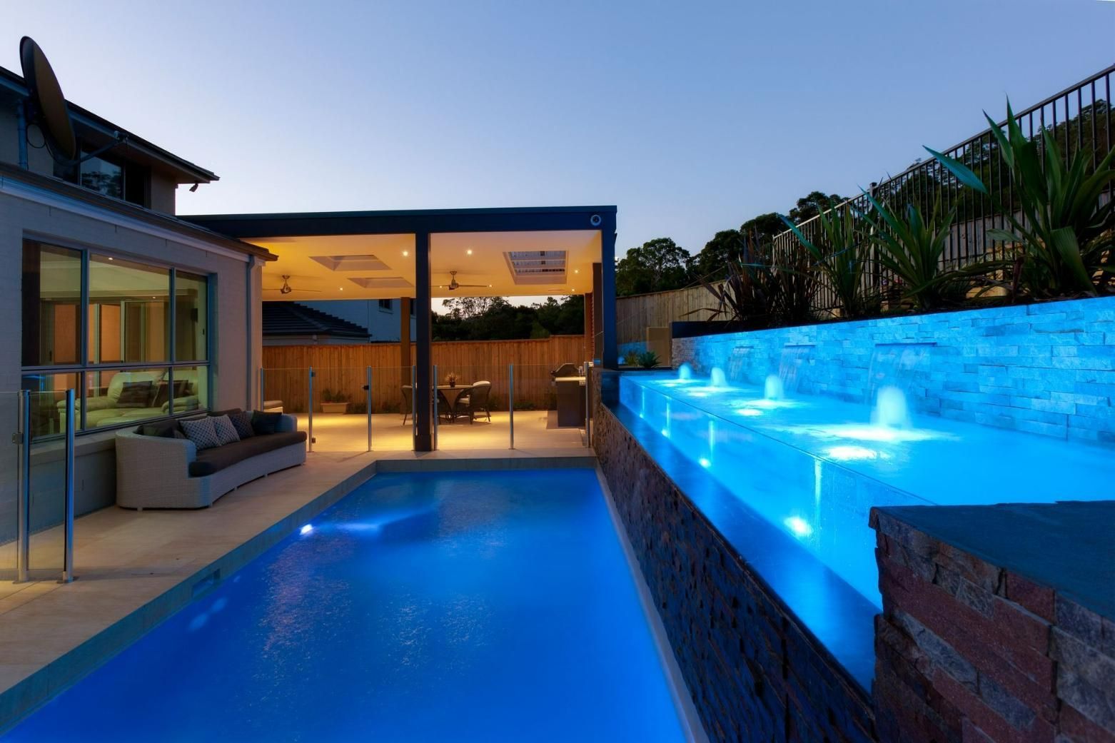 A Large Swimming Pool Is Lit Up At Night In Front Of A House — Glass Pool Windows Australia In Melbourne, VIC