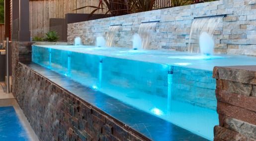 A Swimming Pool With A Waterfall In The Middle Of It — Glass Pool Windows Australia In Old Bar, NSW