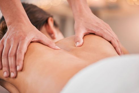 Hände, die während einer Spa-Behandlung den Rücken einer Person massieren