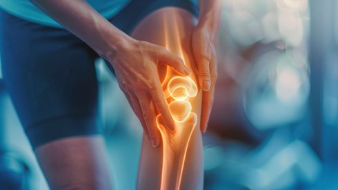 Eine Hand hält ein leuchtendes Kniegelenk und veranschaulicht Knieschmerzen oder eine Verletzung beim Sport