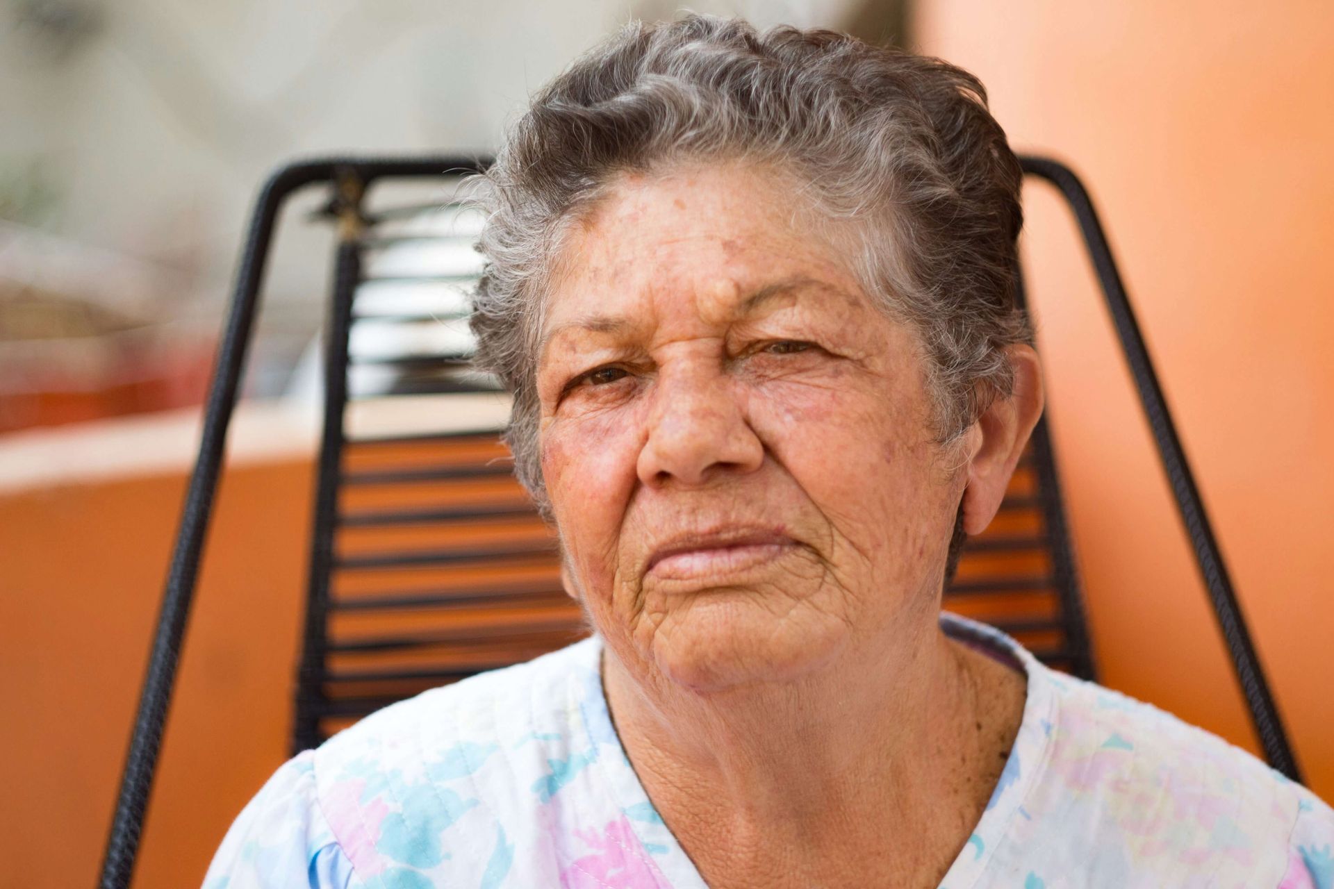 Senhora sentada em uma cadeira de vime preta