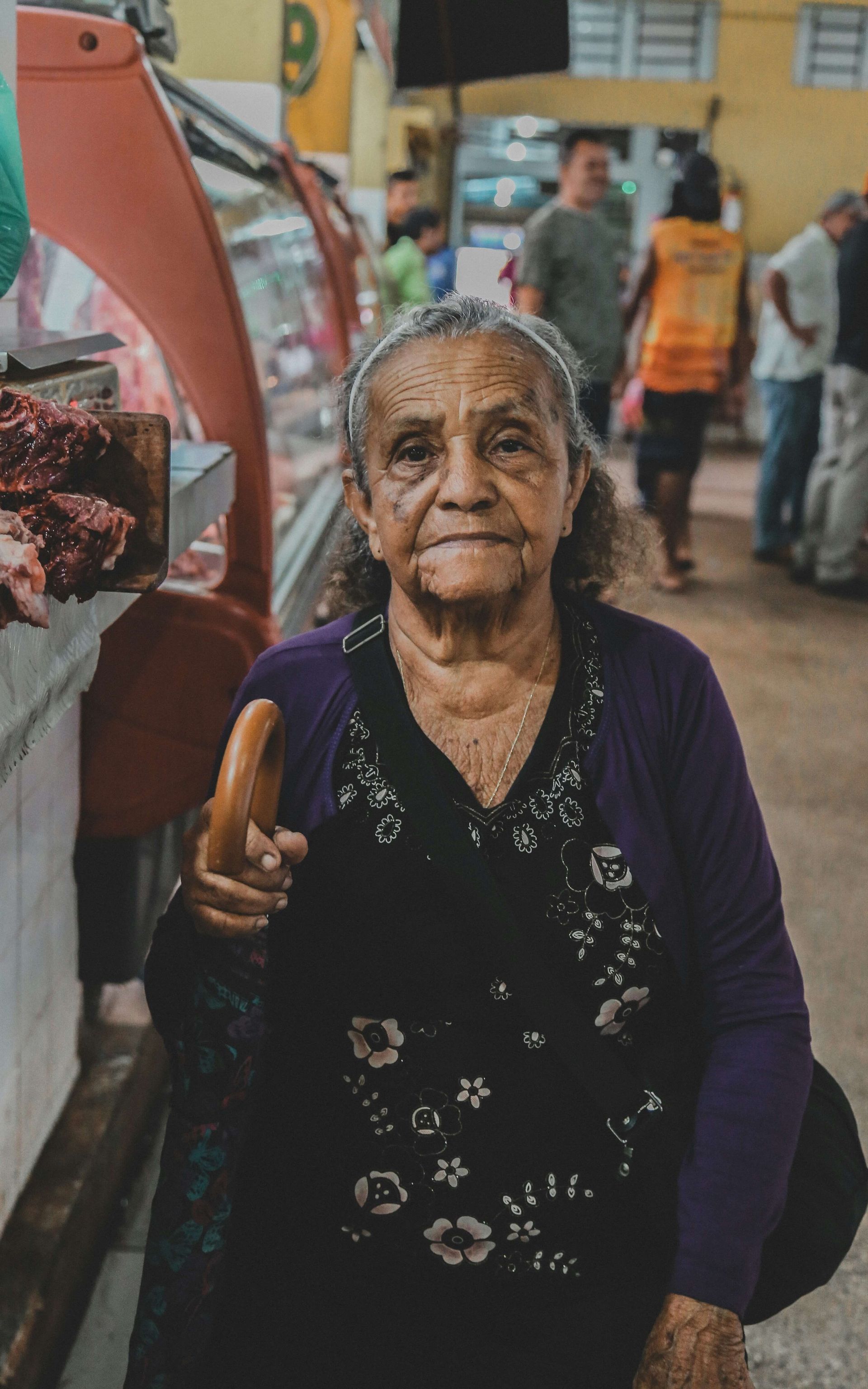 Senha num mercado segurando uma bengala