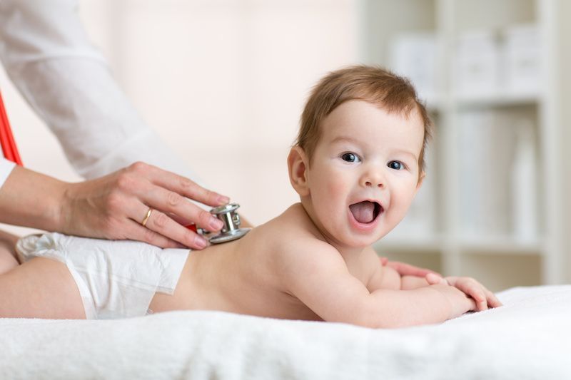 A baby is being examined by a doctor with a stethoscope.