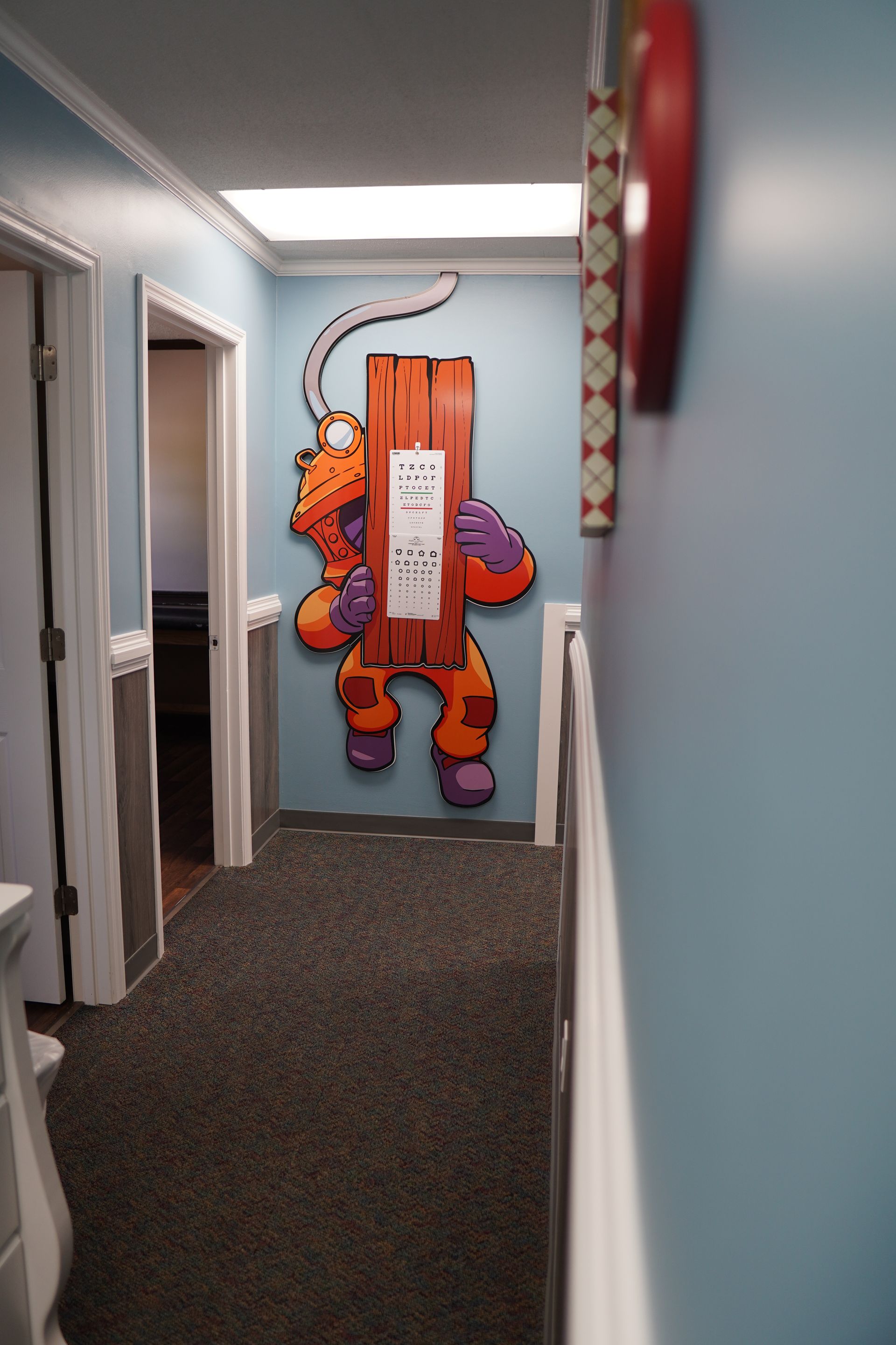 Hallway with a cartoon character holding a wooden sign on a blue wall.