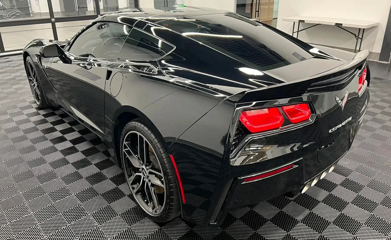Black Corvette sports car on checkered floor.