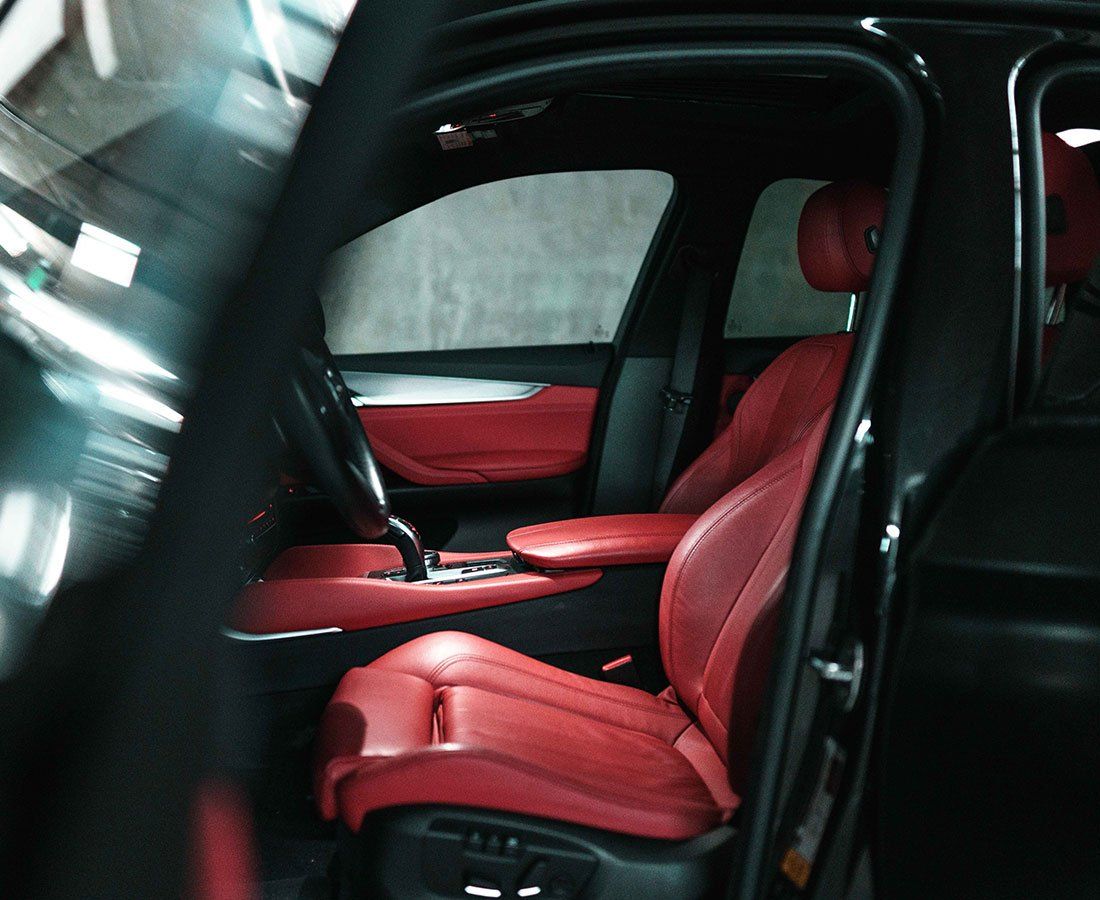 Black car interior with vibrant red leather seats. The driver's seat and dashboard are visible, suggesting luxury and style.