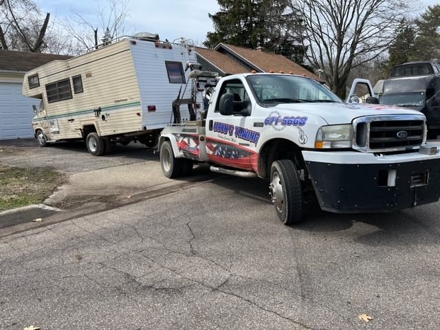 Tow truck hauling a damaged camper trailer on a suburban street