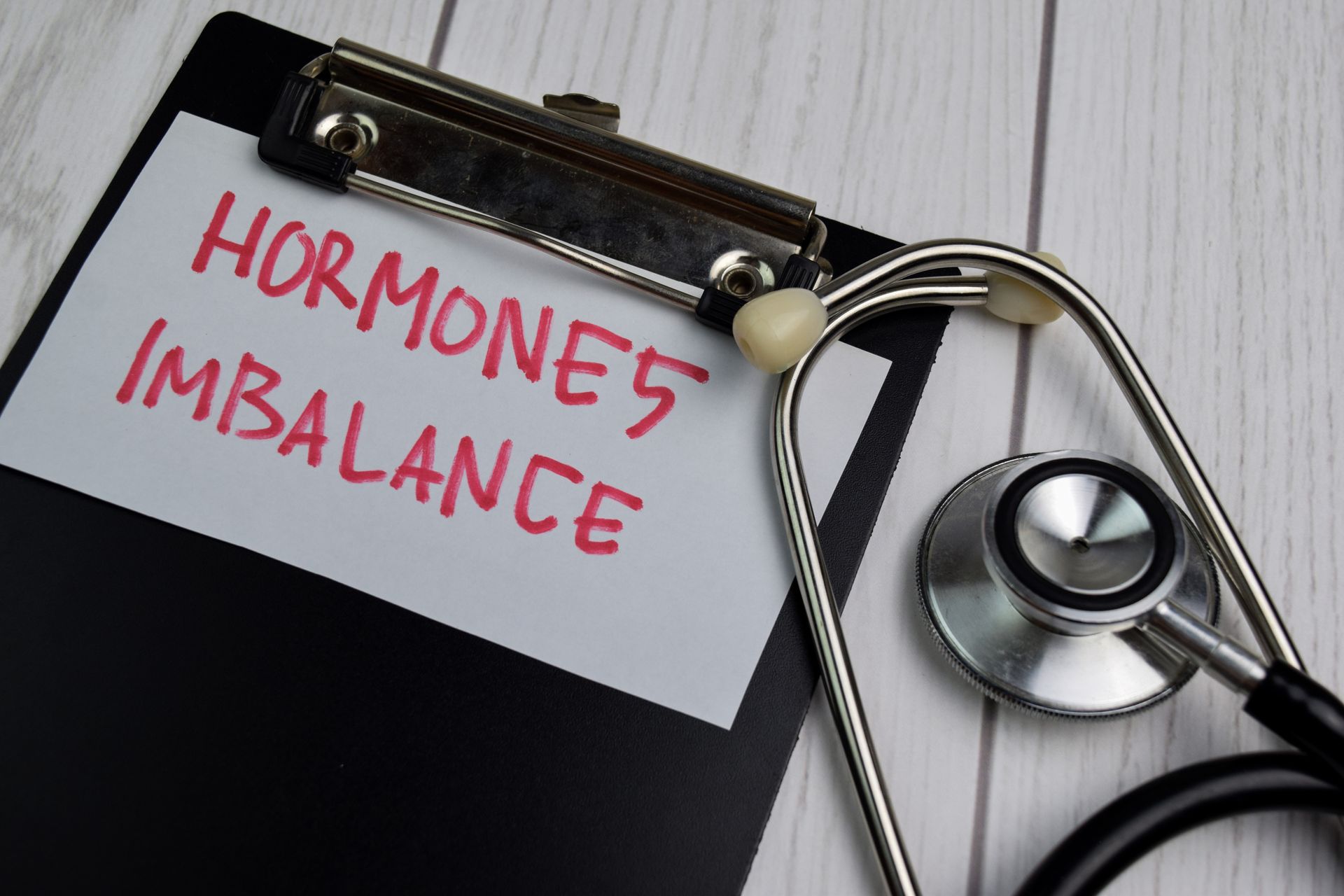 Clipboard with 'Hormone Imbalance' note and a stethoscope on a wooden surface.