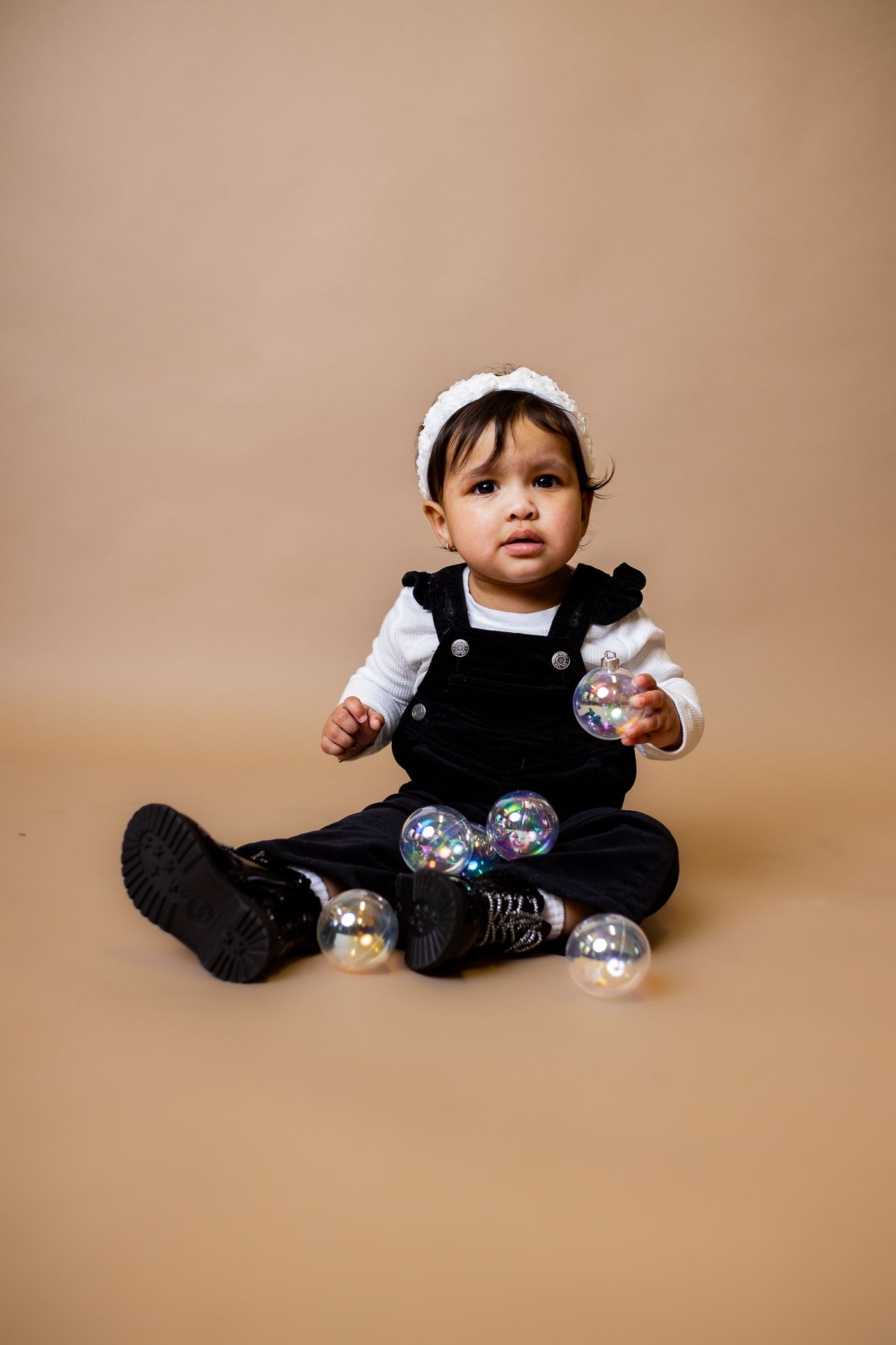 Baby posing on tan background for cake smash session