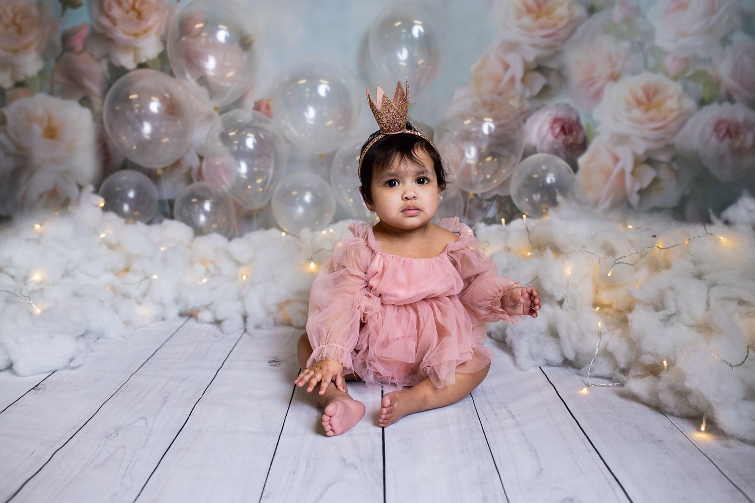 Baby posing on watercolor background for bubble and pink themed cake smash session