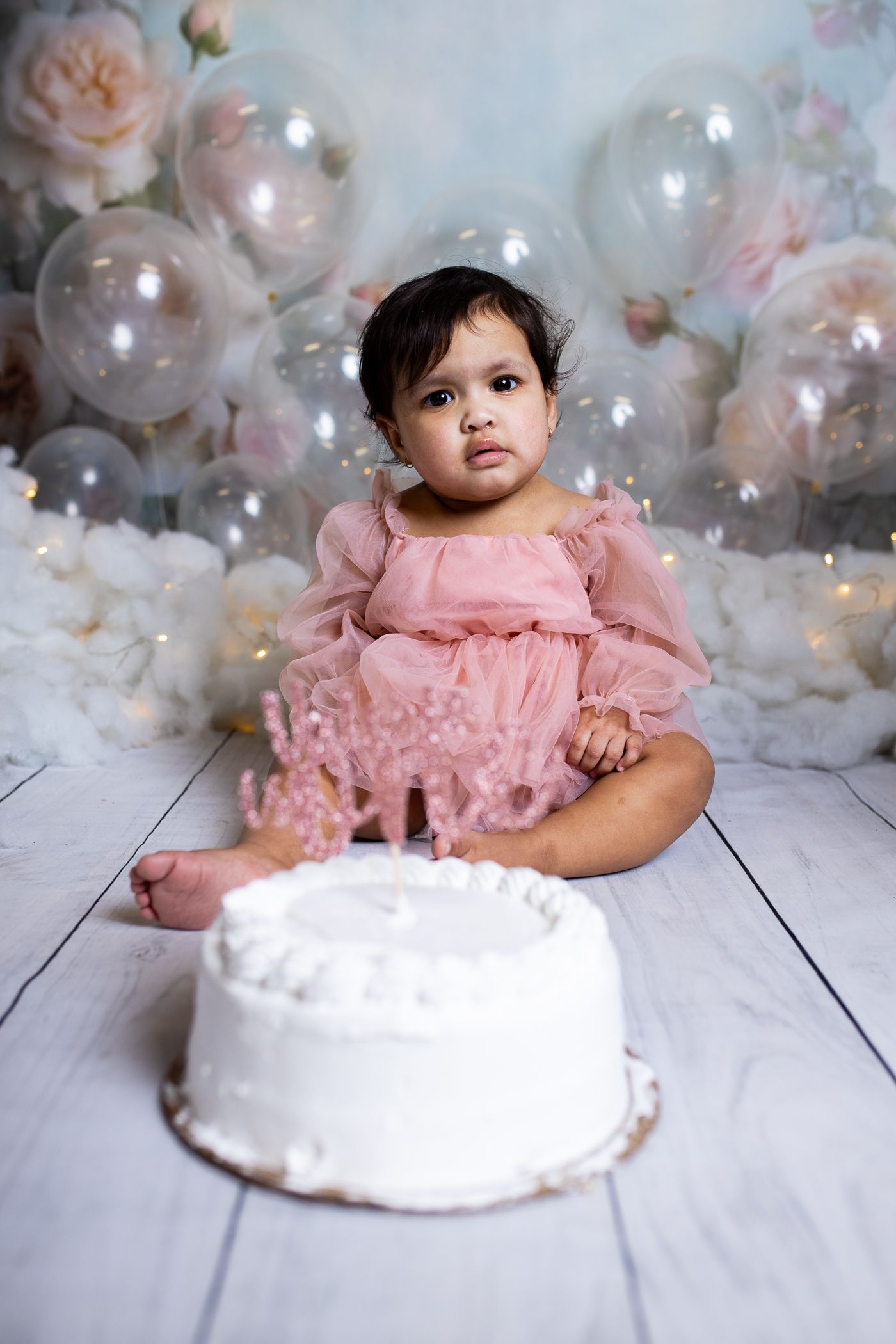 Baby posing on watercolor background for bubble and pink themed cake smash session