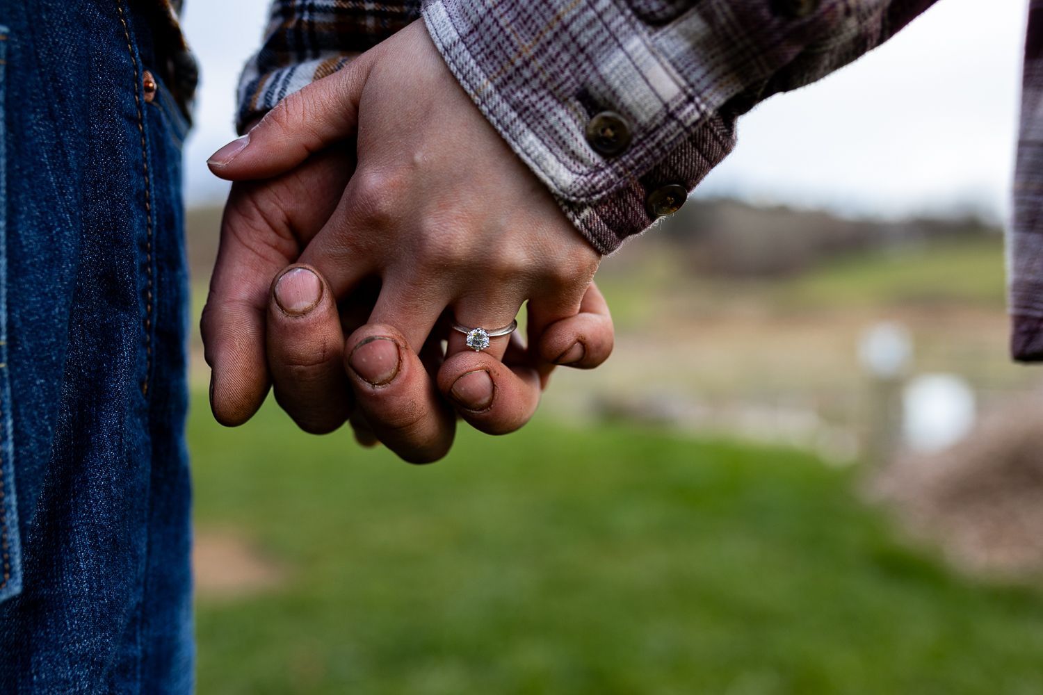 Couple holding hands during engagement session with the ring close-up