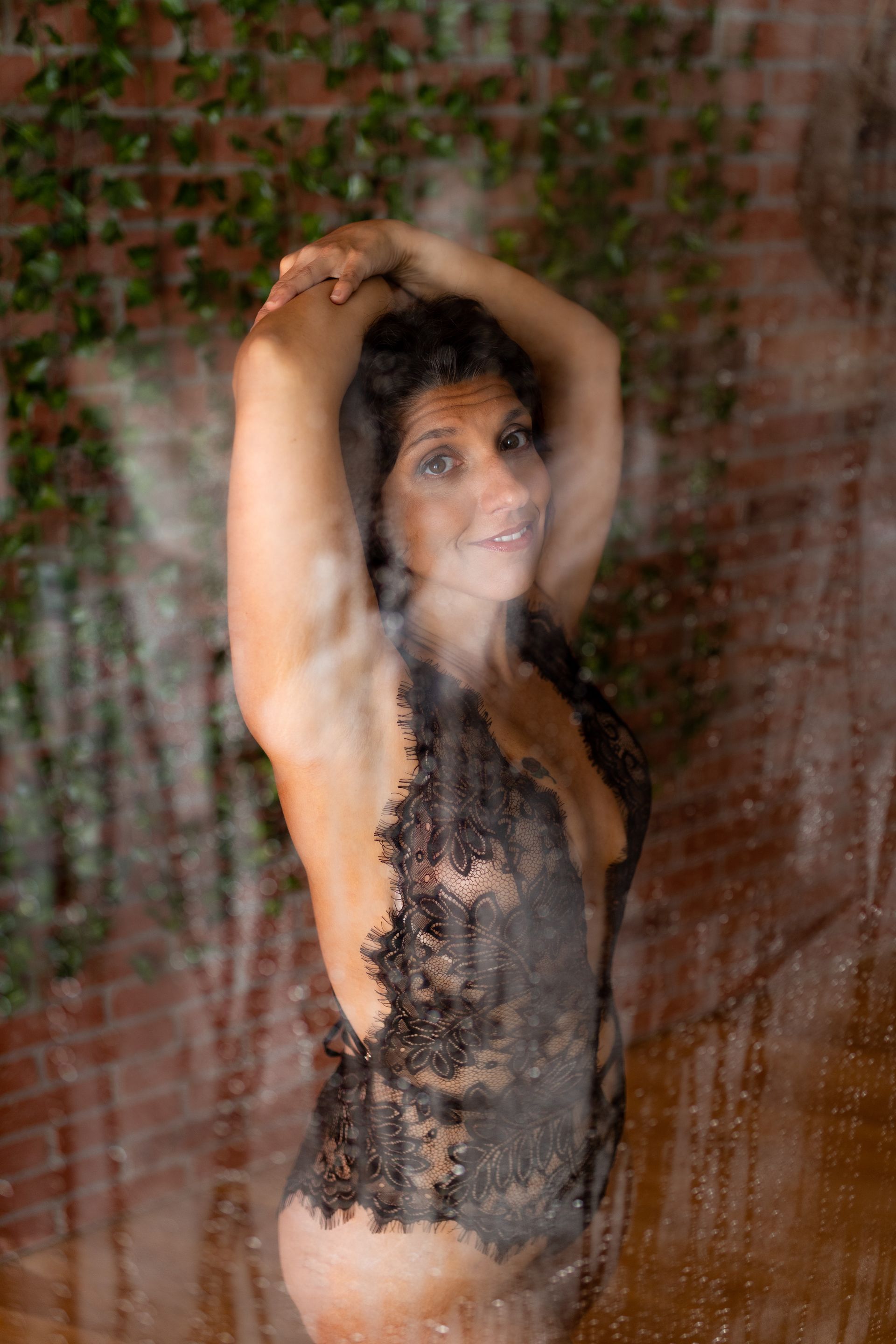 Woman posing in lingerie for boudoir session in a shower scene
