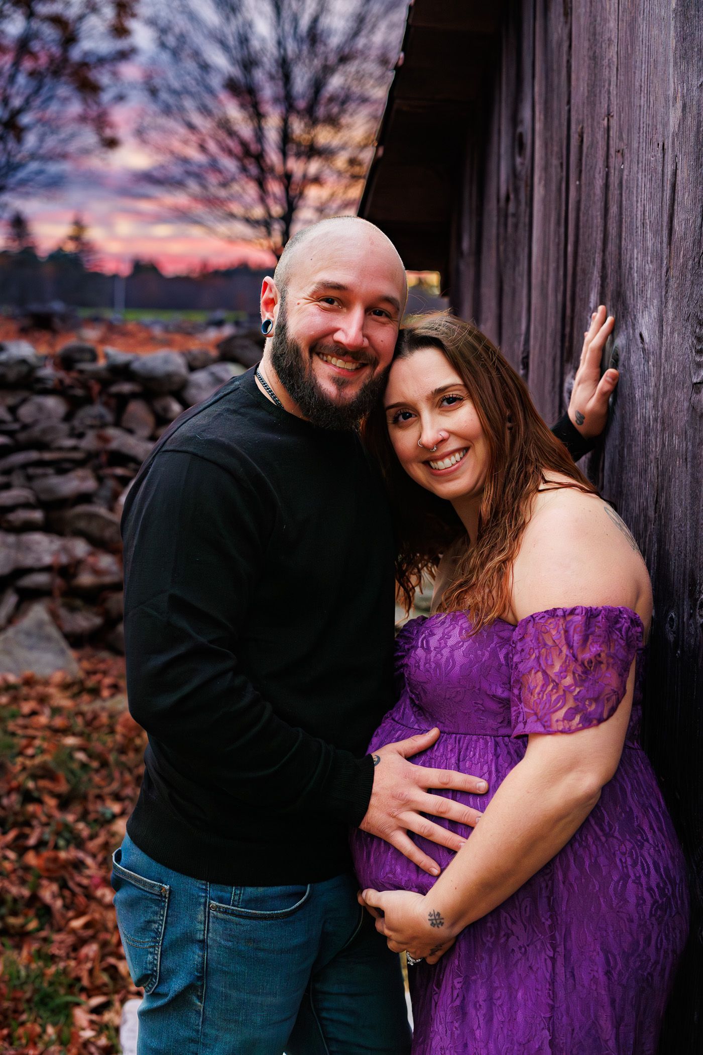 Maternity photography parents posing while snuggling together during sunset