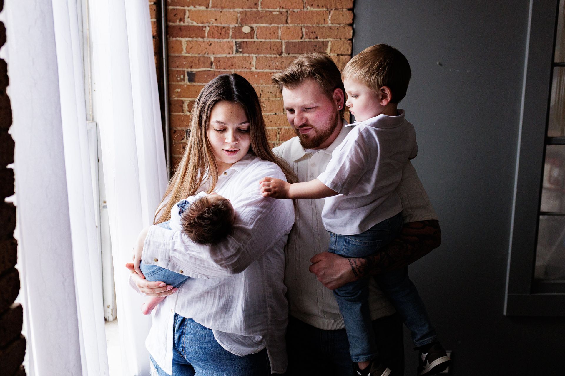 Newborn photography family posing with newborn by window