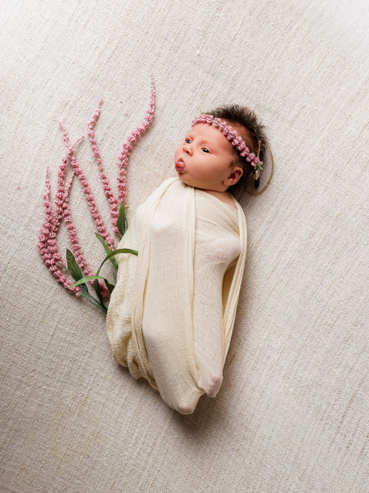 A close up of a newborn baby wearing a hat and sweater.