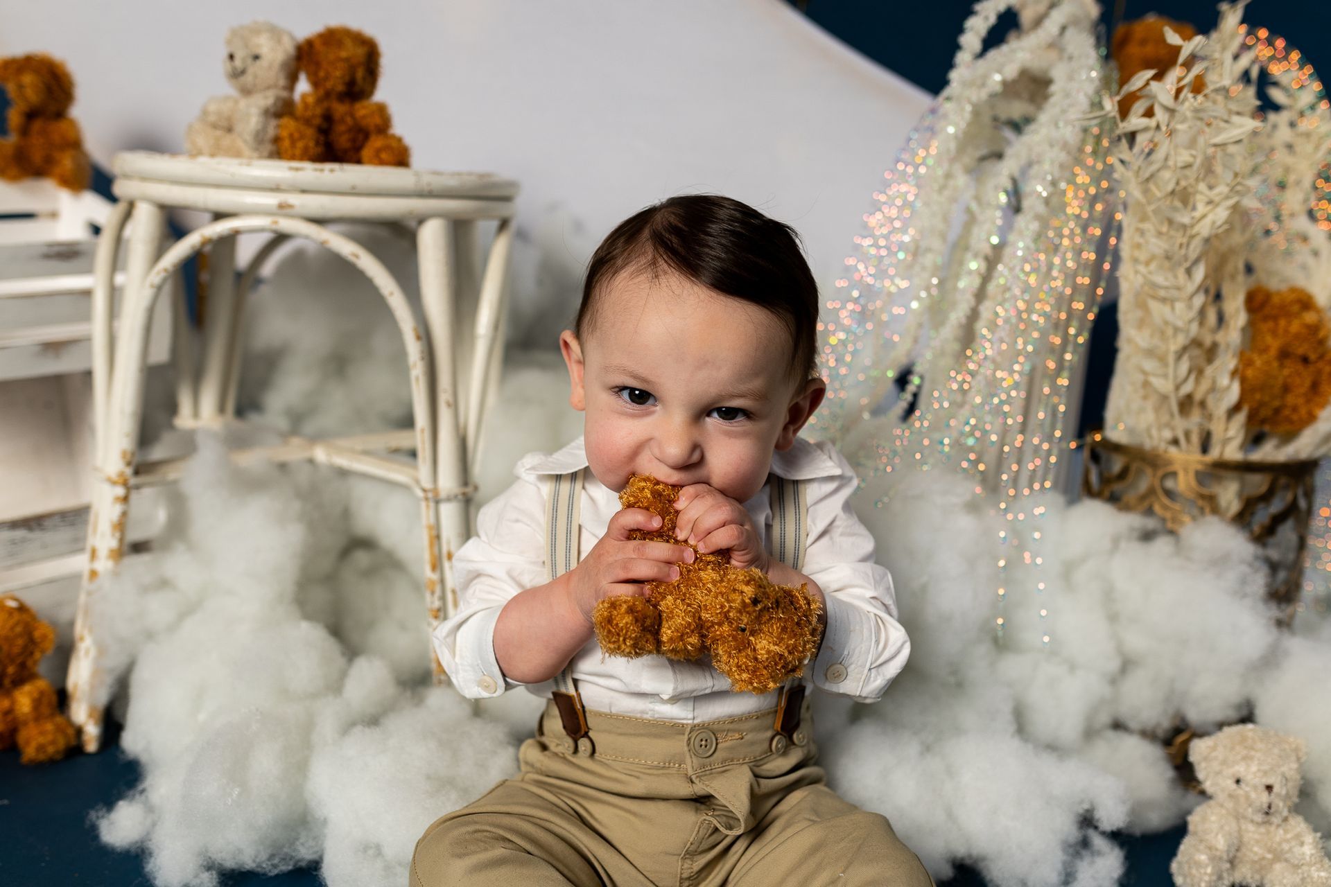 baby standing in a moon-themed studio set with clouds, stars, and teddy bears for cake smash session