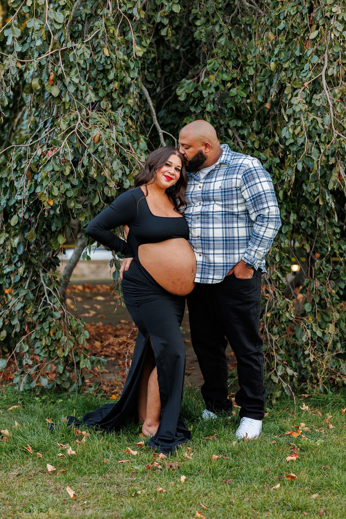 Maternity photography parents posing while dad kisses mom