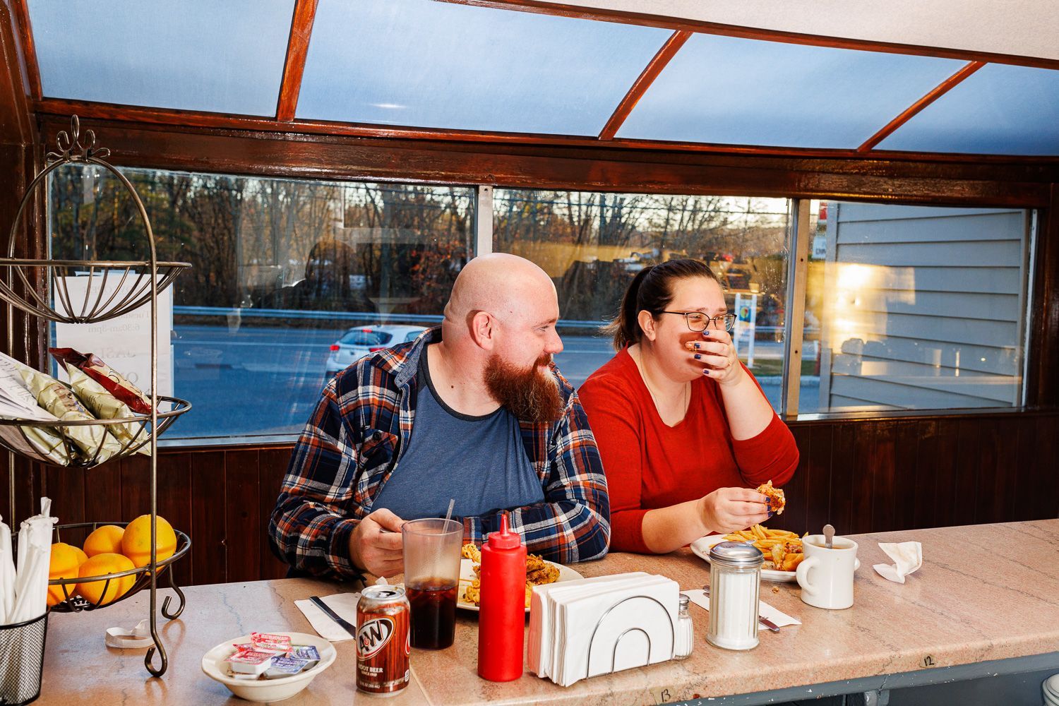 Couple being goofy during an engagement session at a diner