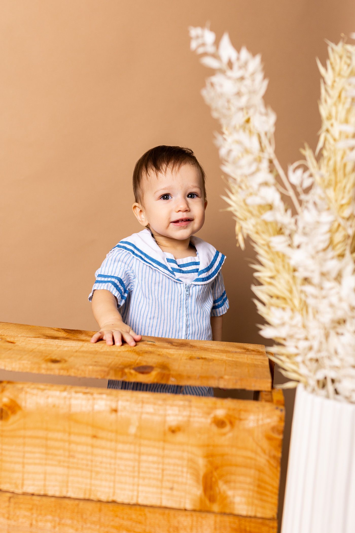 Baby posing on tan background for teddy bear themed cake smash session