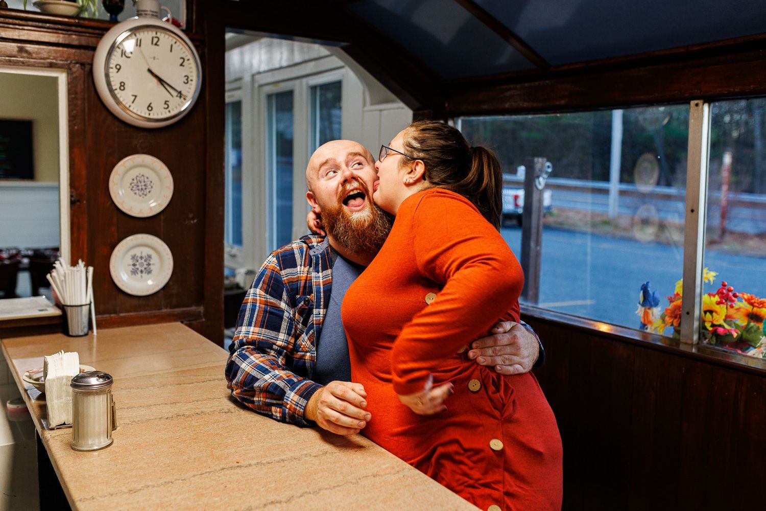 Couple being goofy during an engagement session at a diner