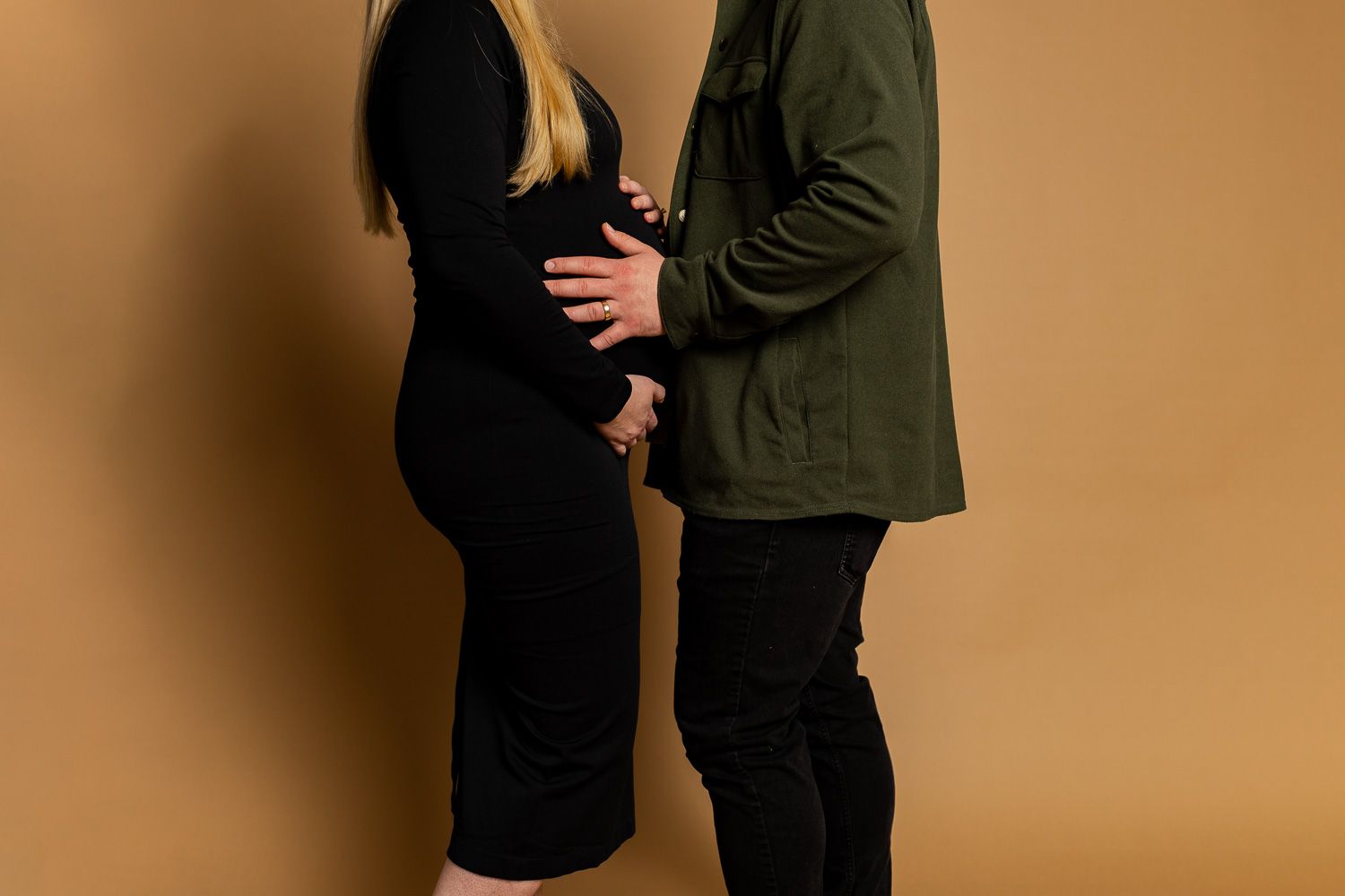 Maternity photography parents posing on tan studio background