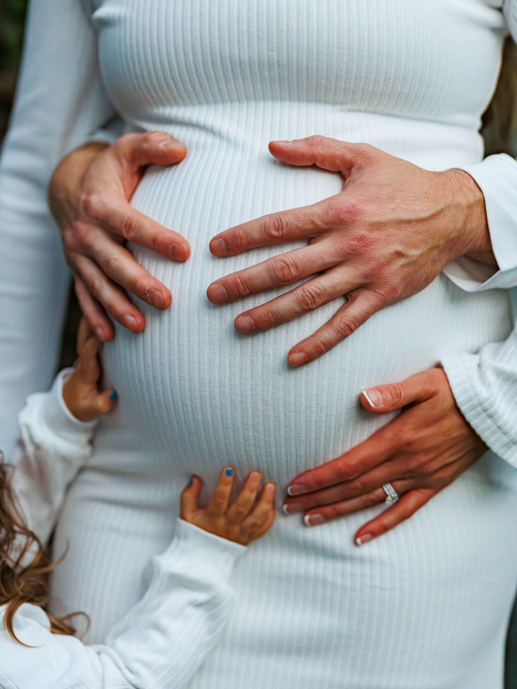 A man is holding a pregnant woman 's belly.