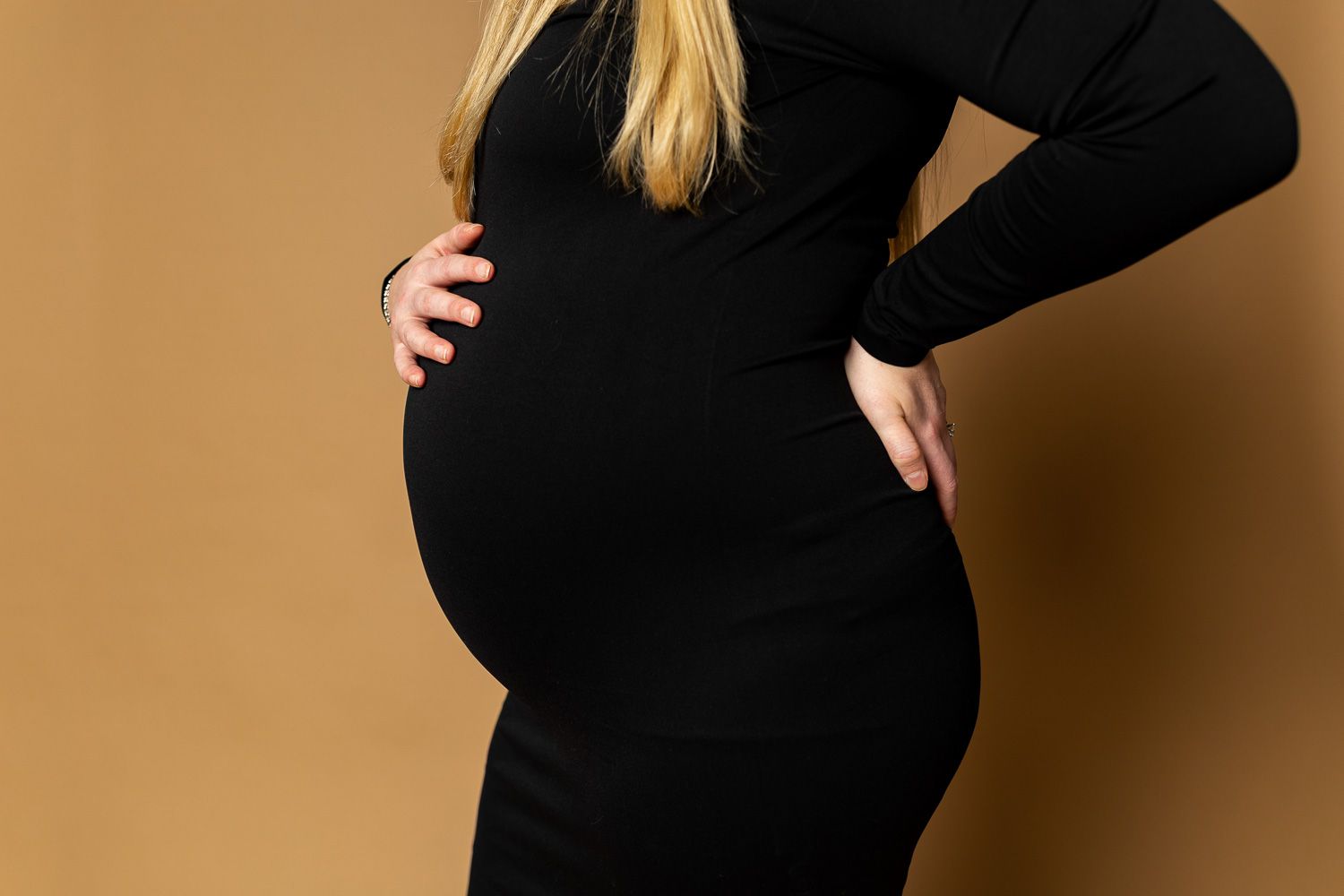 Maternity photography mom posing on tan studio background