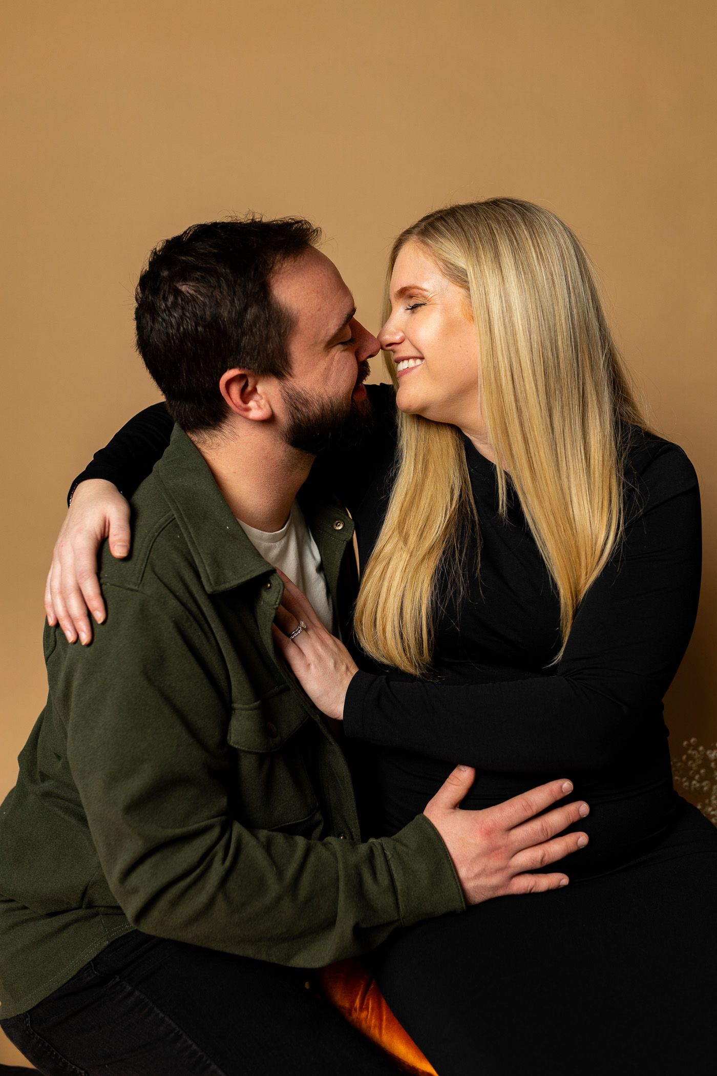 Maternity photography parents posing on tan studio background