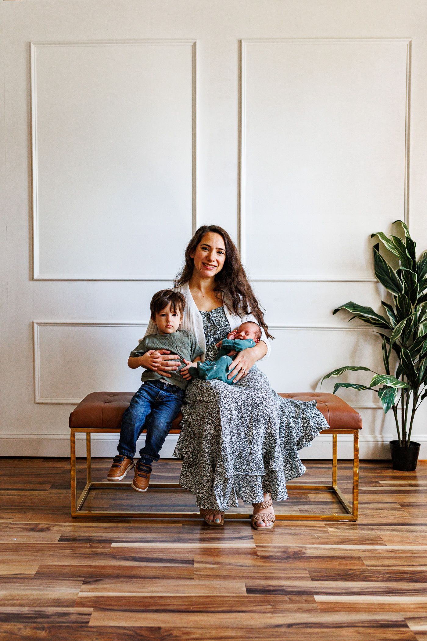 Newborn photography mom posing with toddler and newborn on bench
