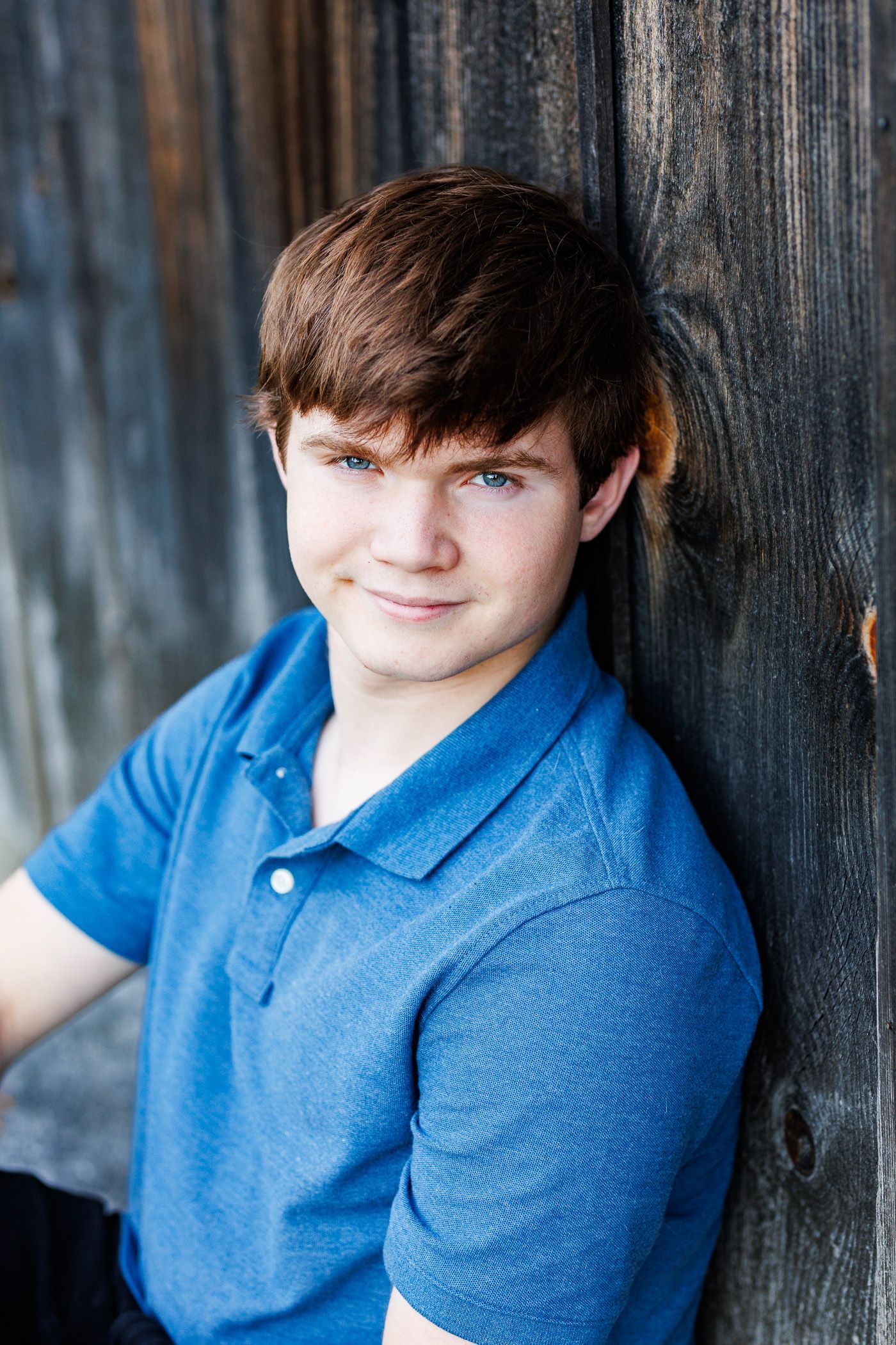 High school senior - senior photography - male student sitting against barn