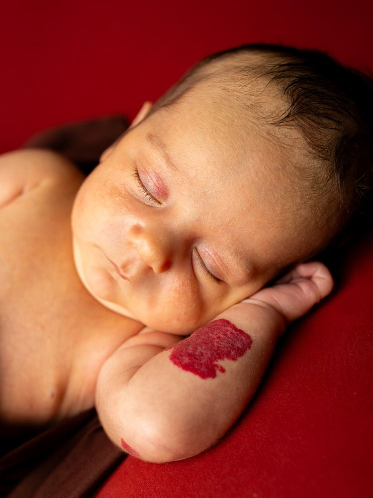 A newborn baby wrapped in a purple blanket