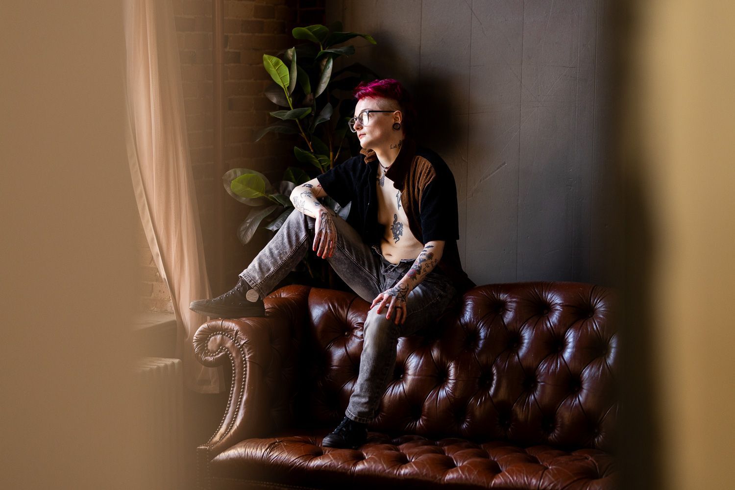 Trans man posing on couch for masculine inspired boudoir session