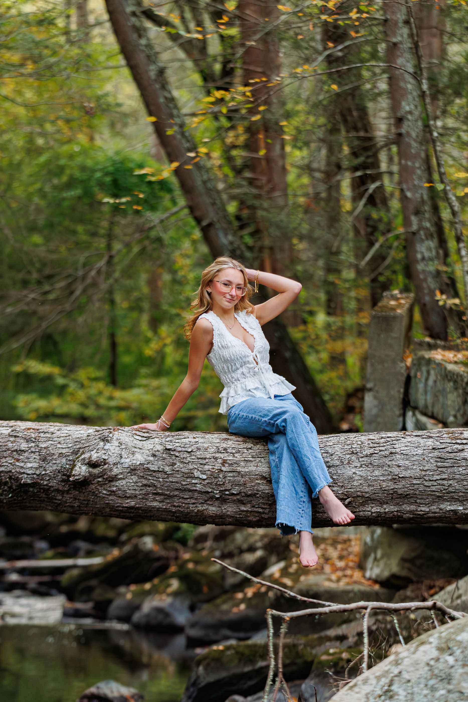 High school senior girl sitting on a fallen log in the woods - high school senior session