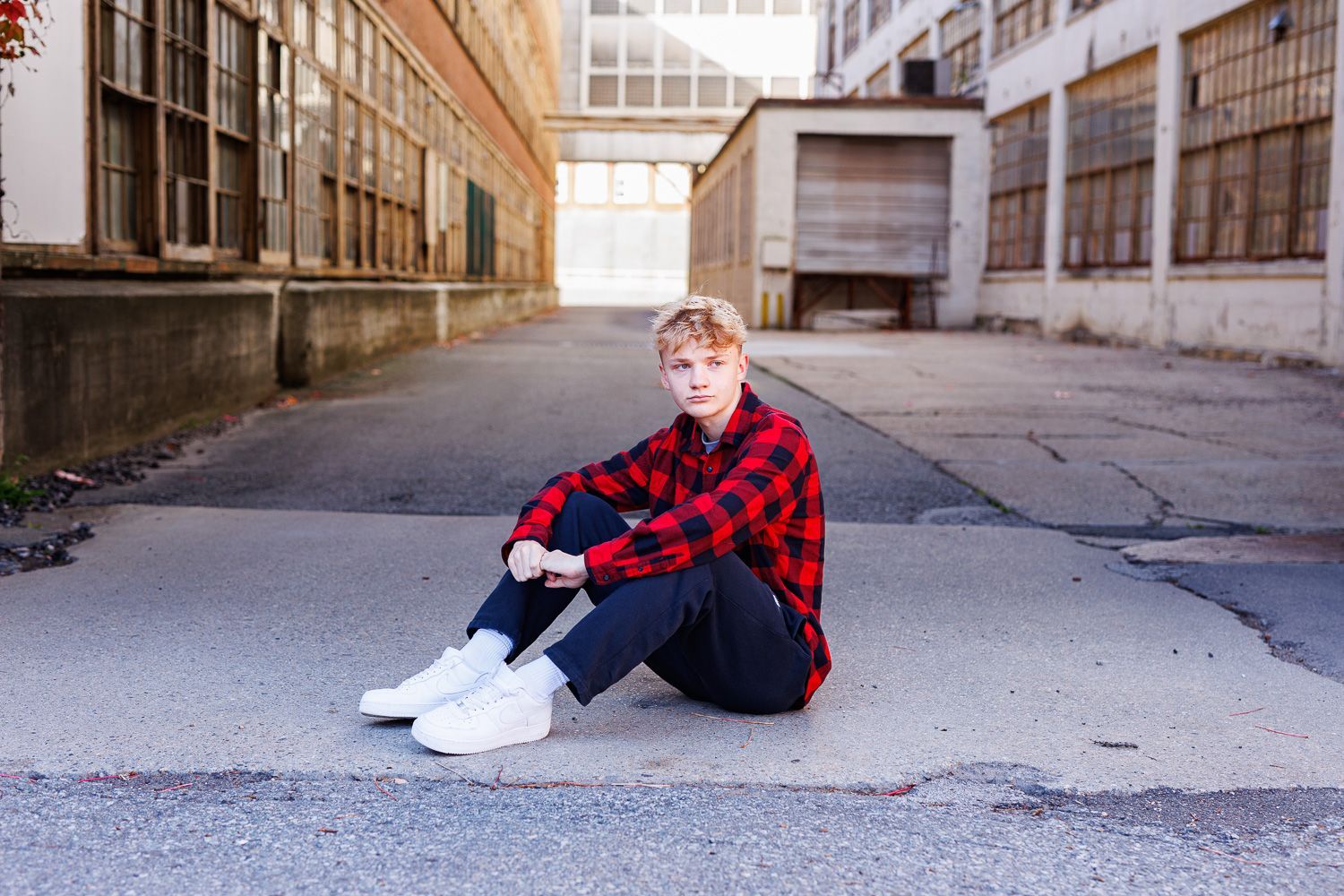 High school senior - senior photography - male student sitting in industrial setting