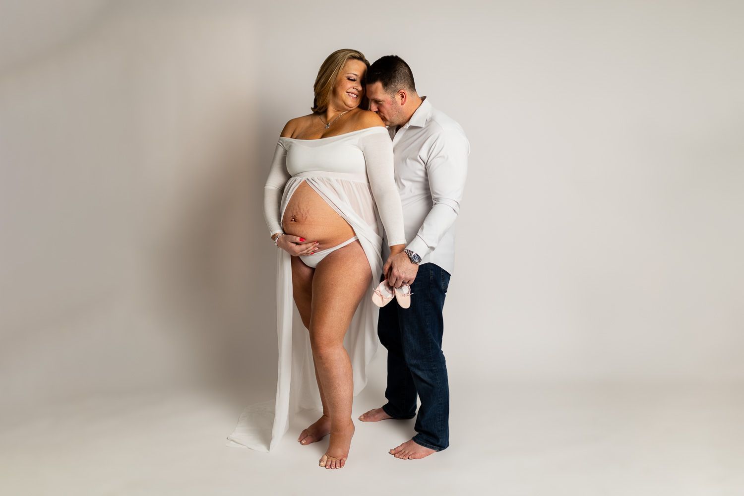 Maternity photography parents on white studio background snuggling