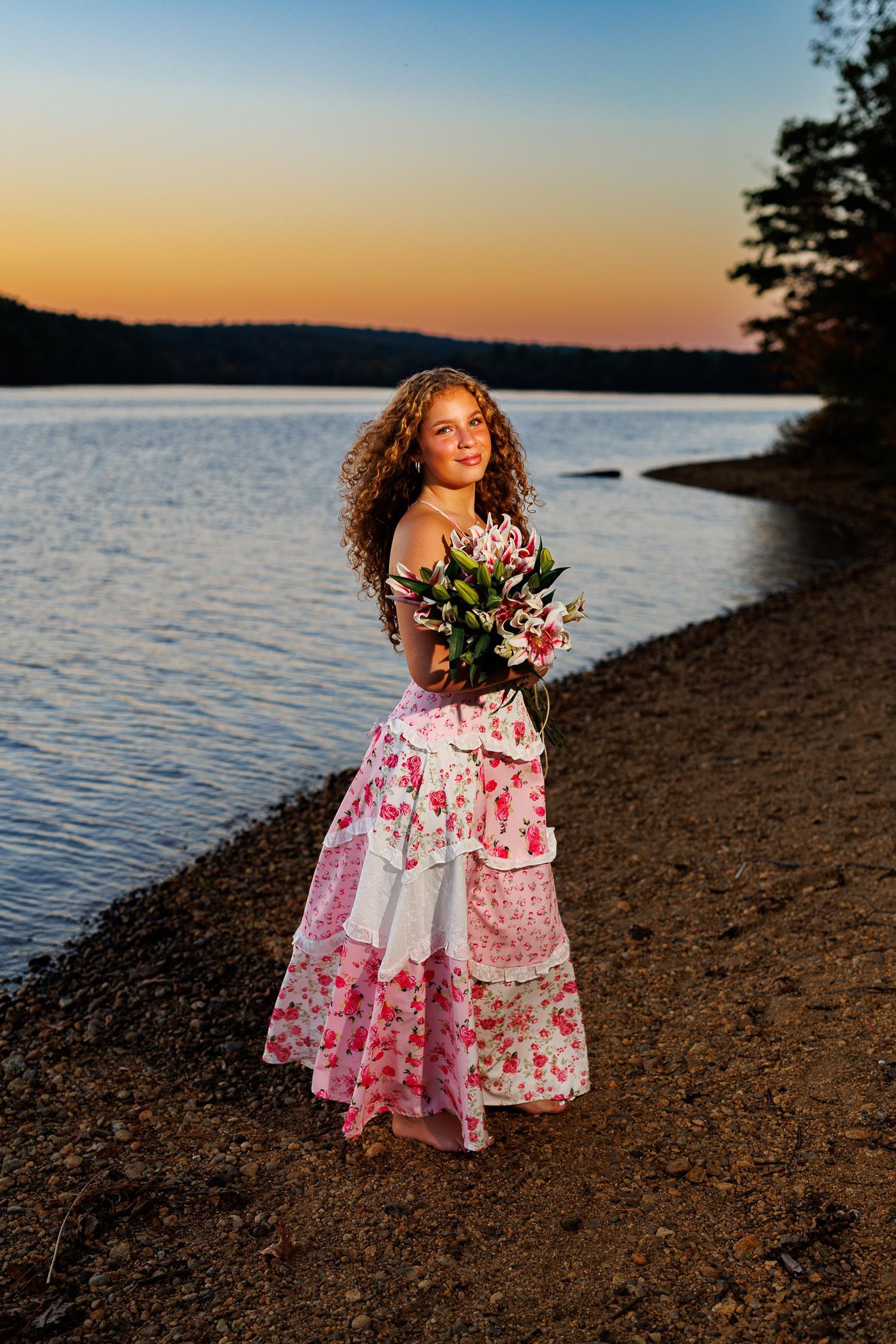 High school senior - senior photography - female student posing in front of sunset holding lillies