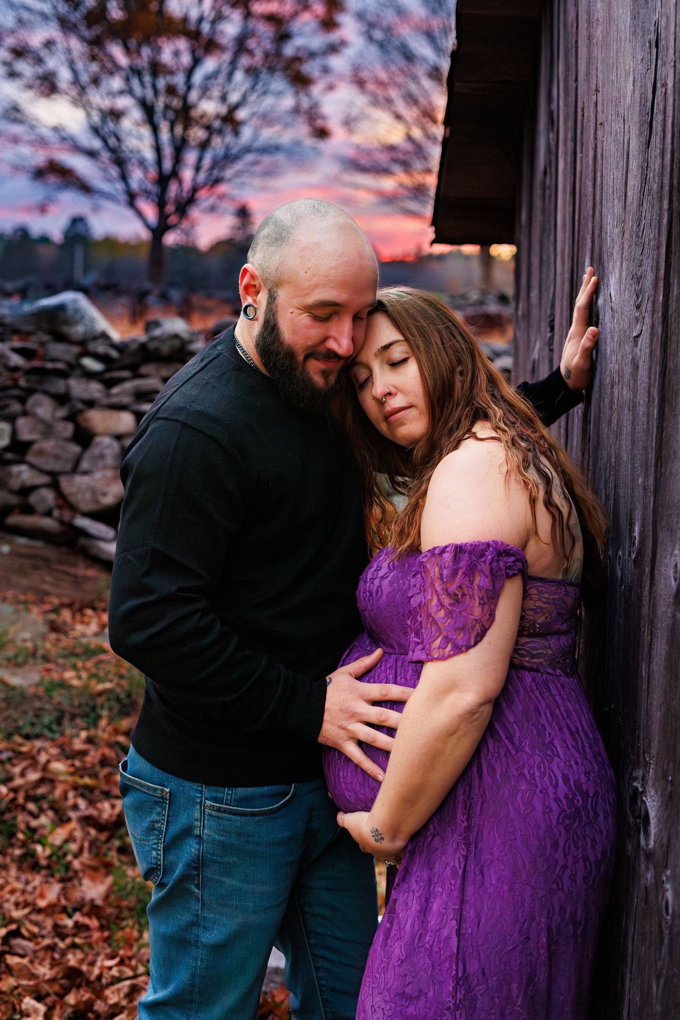 Maternity photography parents posing while snuggling together during sunset