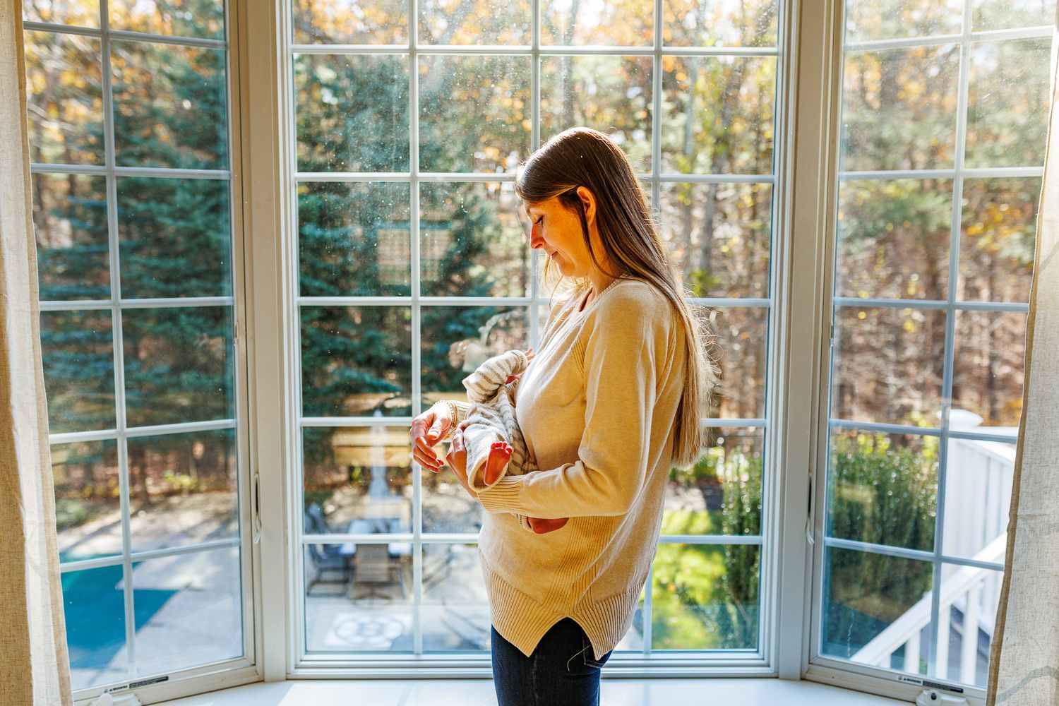 Newborn photography mom holding baby by window