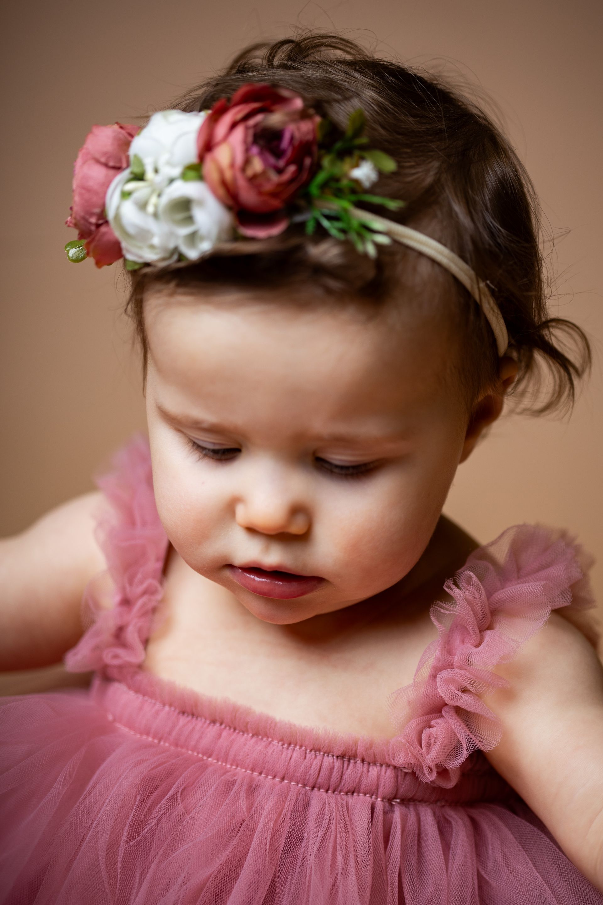 Baby posing on pink background for flowers and tulle themed cake smash session