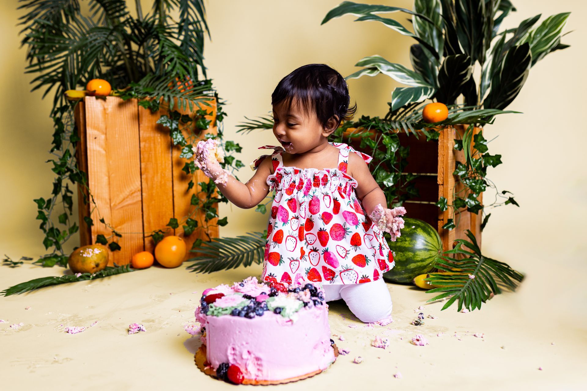 Baby posing on yellow background for citrus and jungle themed cake smash session