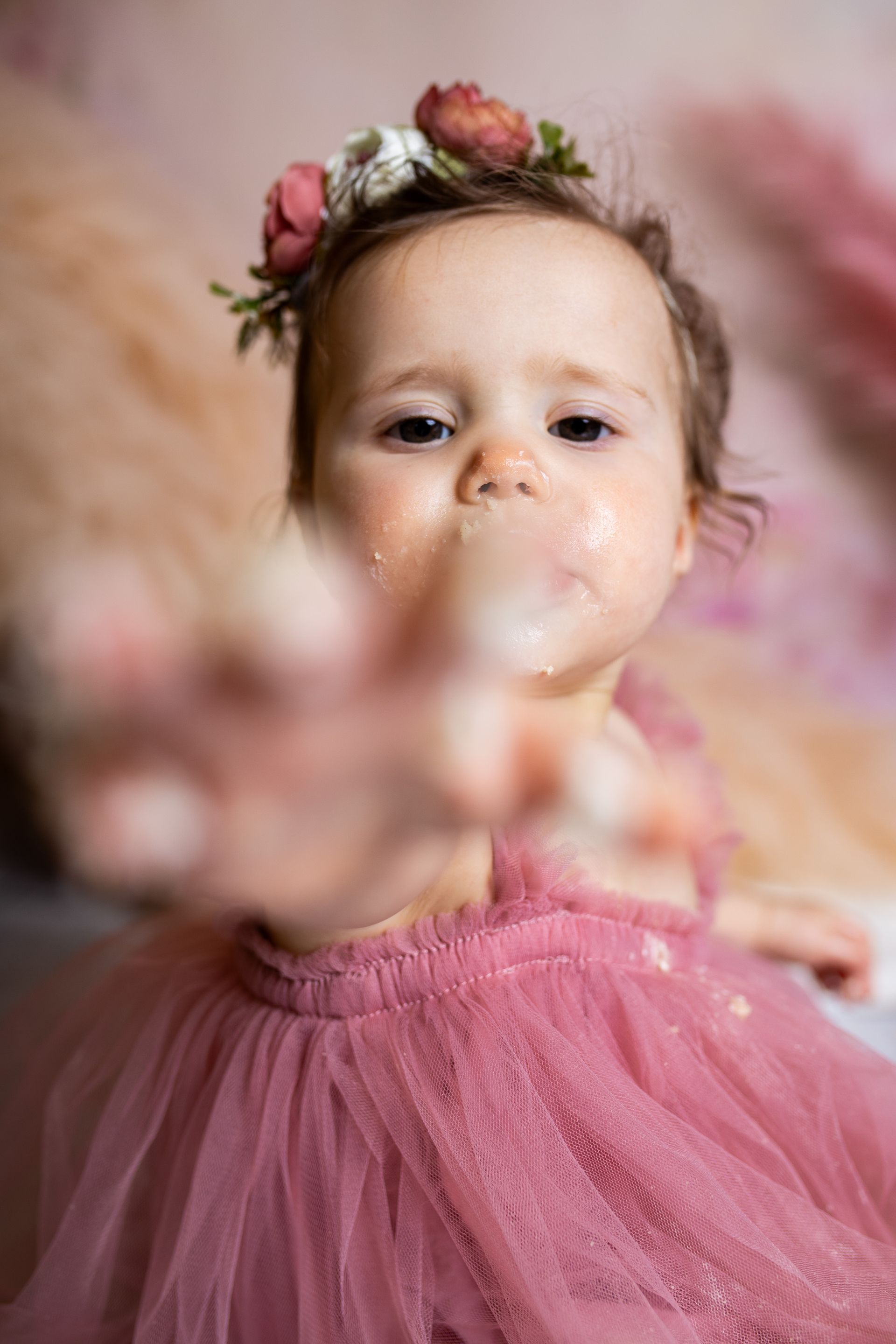 Baby posing on pink background for flowers and tulle themed cake smash session