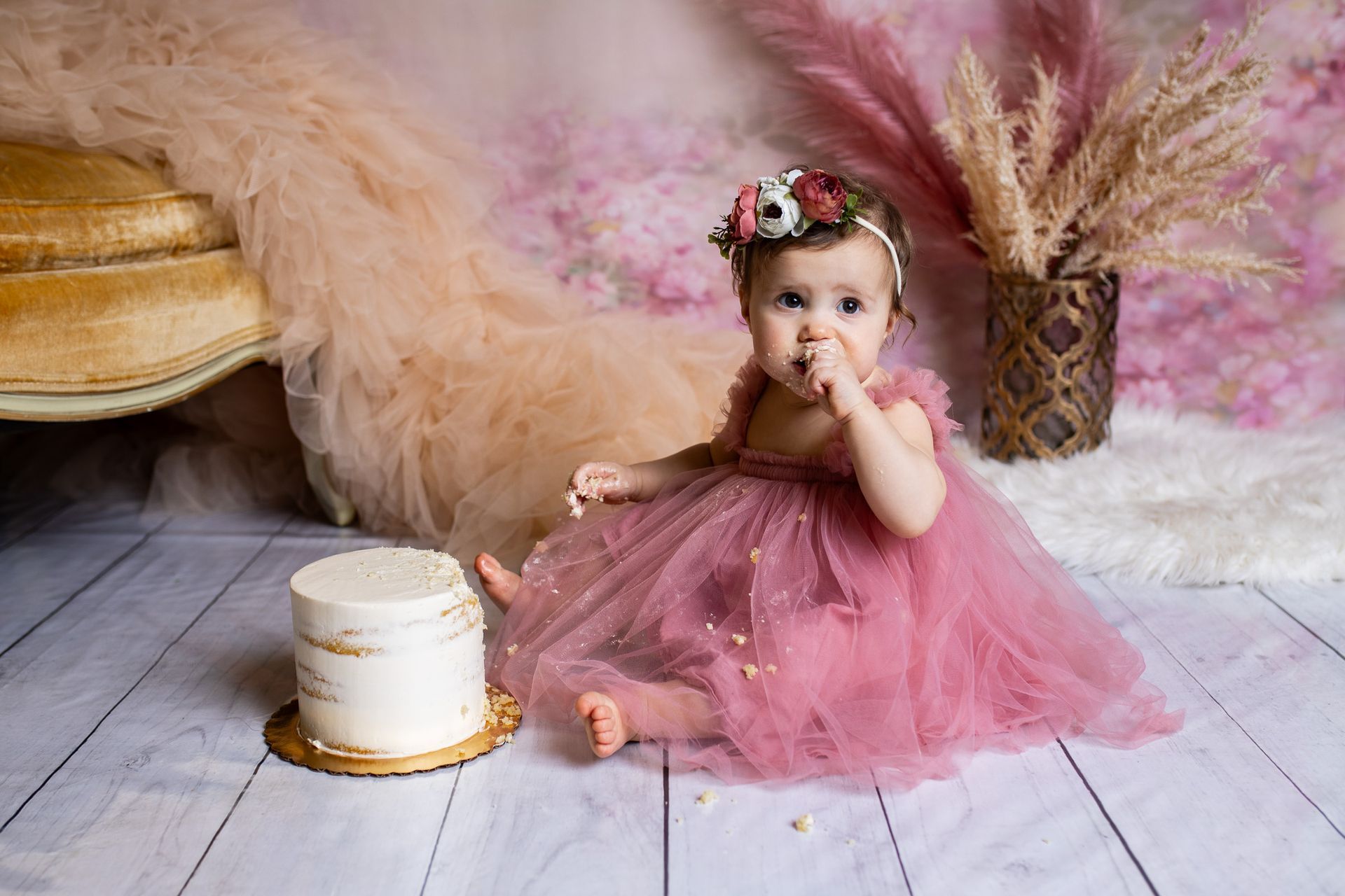 Baby posing on pink background for flowers and tulle themed cake smash session