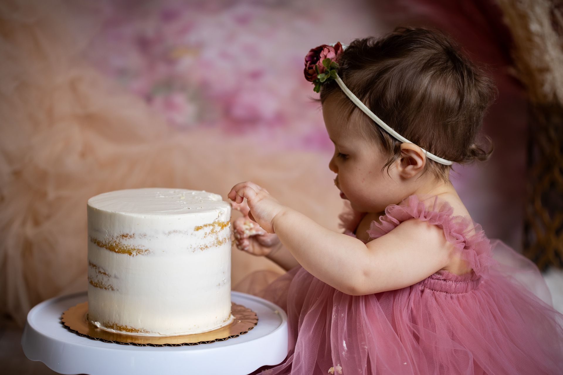 Baby posing on pink background for flowers and tulle themed cake smash session