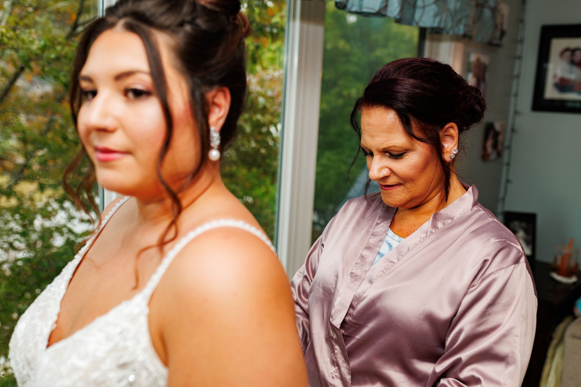 Mom helping bride get dress on for wedding